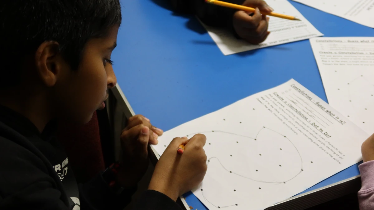 a young boy draws a constellation of stars