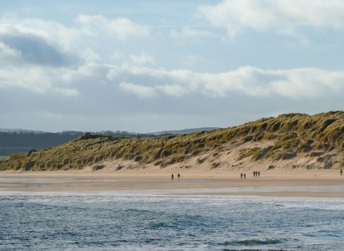 People walking along Beadnell Bay