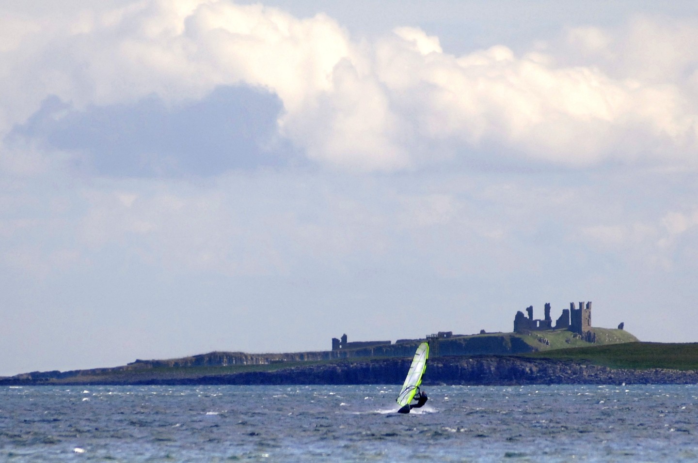 Windsurfer on the sea in front of Dunstanburgh Castle