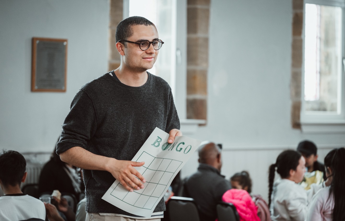 Young man holding piece of paper with bingo game on