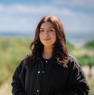 Lady with brown hair smiling on sand dune